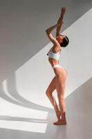 View, from the ,side. Young caucasian woman with slim body shape is indoors in the studio photo