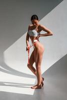 Beautifu,l shadows from sunlight. Young caucasian woman with slim body shape is indoors in the studio photo