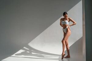 Posing, in the sunlight. Young caucasian woman with slim body shape is indoors in the studio photo