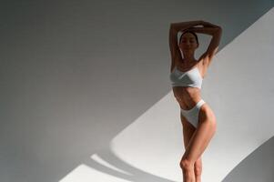 Against wall. Young caucasian woman with slim body shape is indoors in the studio photo