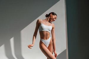 Illuminated by, sunlight. Young caucasian woman with slim body shape is indoors in the studio photo