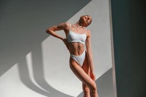 Illuminated by sunlight. Young, caucasian woman with slim body shape is indoors in the studio photo