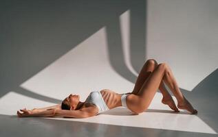 Resting, on, the floor. Young caucasian woman with slim body shape is indoors in the studio photo