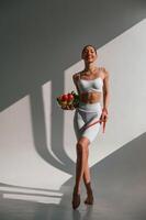 Conception of diet. With vegetalbes and fruits. Young caucasian woman with slim body shape is indoors in the studio photo