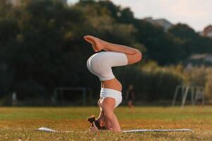 Head stand ,exercise. Young caucasian woman with slim body shape is in the fitness clothes outdoors photo
