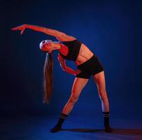 Warm ,up exercises. Beautiful muscular woman is indoors in the studio with neon lighting photo