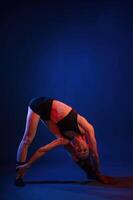In studio with, red and blue neon lighting. Beautiful muscular woman is indoors photo