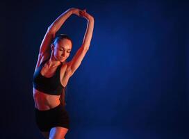 Warm up exercises.. Beautiful muscular woman is indoors in the studio with neon lighting photo