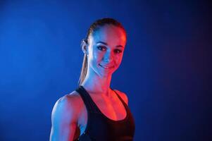 Portrait of beautiful muscular woman that is indoors in the studio with neon lighting photo