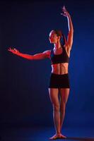 Standing, posing.. Beautiful, muscular woman is indoors in the studio with neon lighting photo