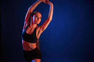 Warm ,up exercises.. Beautiful muscular woman is indoors in the studio with neon lighting photo