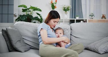Portrait of Beautiful mother holds her baby close to her chest and hums softly to lull her baby to sleep on the cozy sofa at home. photo