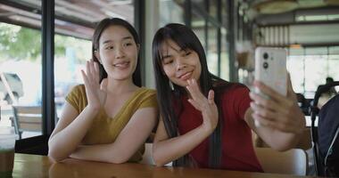 Portrait of Two Asian women are enjoying talking with a friend via call on mobile phone at a table in a coffee shop. Family enjoying time together. Happy lifestyle. photo