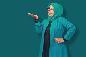 A confident Muslim businesswoman wearing a stylish green hijab and blazer, presenting with an open hand gesture. Perfect for concepts of leadership, professionalism, and career success photo