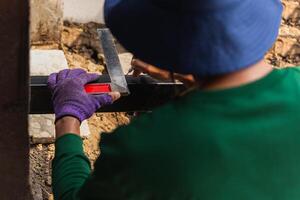Male worker measuring iron with metal ruler in building site photo