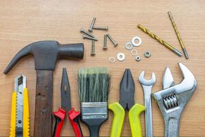 Collection of various used hand tools organized on a wooden surface for construction tasks photo