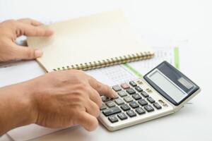 Hand pressing buttons on calculator while preparing financial reports in an office setting photo