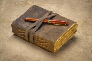 retro leather bound journal with decked edge handmade paper pages and a stylish pen, journaling concept photo