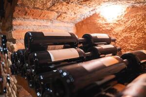 A wine cellar with bottles neatly stacked on their sides, rustic brick and stone walls, and soft lighting highlighting the organized display. photo