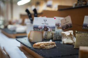A curated display of gourmet cheeses on a slate platter, highlighting Tresor d'Isigny with a cow icon and French flag, set in an upscale indoor setting. photo
