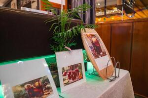 A table with drink menus for Gluhwein, Kinderpunsch, and Punsch, adorned with a potted plant and set against wooden paneling and warm lighting. photo