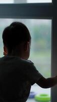 Agile little toddler opens the door. Kid walks to a balcony where his toys are. Vertical video