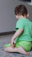 One year old toddler plays with a toy car at home. Rear view of a child having fun. Vertical video
