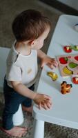 Toddler baby learning fruit. Caucasian child plays on the little table. View from top. Vertical video