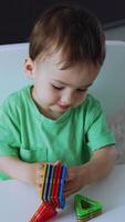 Little boy plays with toys of different geometrical shape. Adorable toddler is talking while playing. Top view. Vertical video
