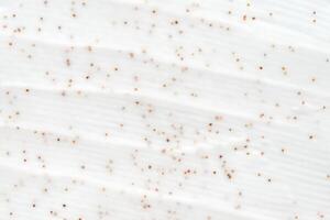 Close up of white cream with exfoliating beads and smooth textured surface. photo