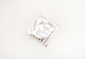 Glossy-packaged condoms on a plain white background. photo
