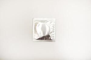 Iridescent condom packs against a white background. Male birth control sheaths. photo