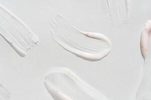Smooth white cream smears on light background highlighting texture and skincare elements. photo