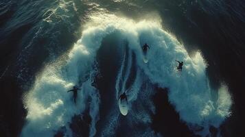 Aerial view of surfers riding waves at sunset photo