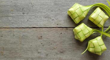 Ketupat Rice Dumpling On table Wood Background. Ketupat is a natural rice casing made from young coconut leaves during eid Mubarak photo