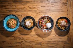 Four bowls of food are arranged on a wooden table photo