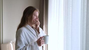 woman waking up and drinking hot coffee standing next to window, morning routine video