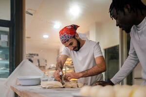 Two men in white shirts and red bandanas are making bread photo