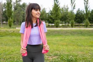 A woman is standing in a field with a pink scarf. photo