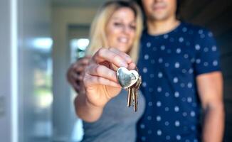 A man and woman holding keys in front of a house photo