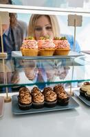 A woman looking at cupcakes in a display case photo