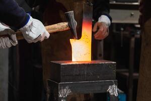 A person is using a hammer to make a piece of metal art. photo