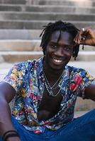 A man with dreadlocks sitting on steps smiling photo