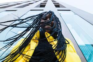 A woman with dreadlocks is standing in front of a building photo