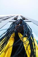 A woman with dreadlocks standing in front of a tall building photo