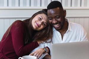 A man and woman are smiling while sitting in front of a laptop photo