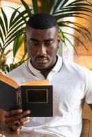 A man is reading a book while sitting at a table photo