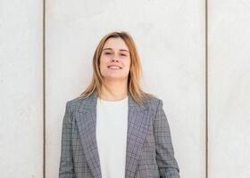 A woman in a suit standing in front of a wall photo