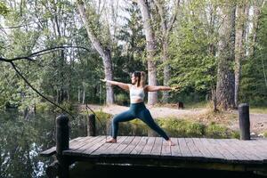 A woman in yoga pose on a dock by a lake photo