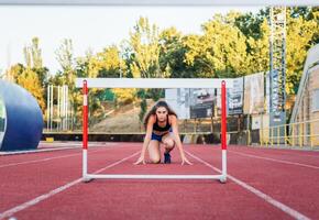 A woman crouches down on a track while running photo
